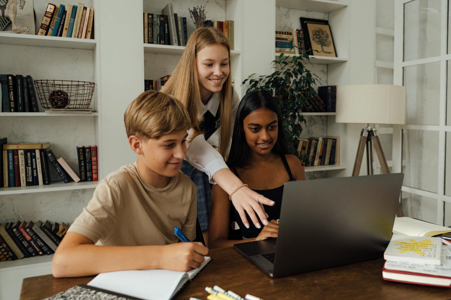 Group of teenagers studying together with laptop and books