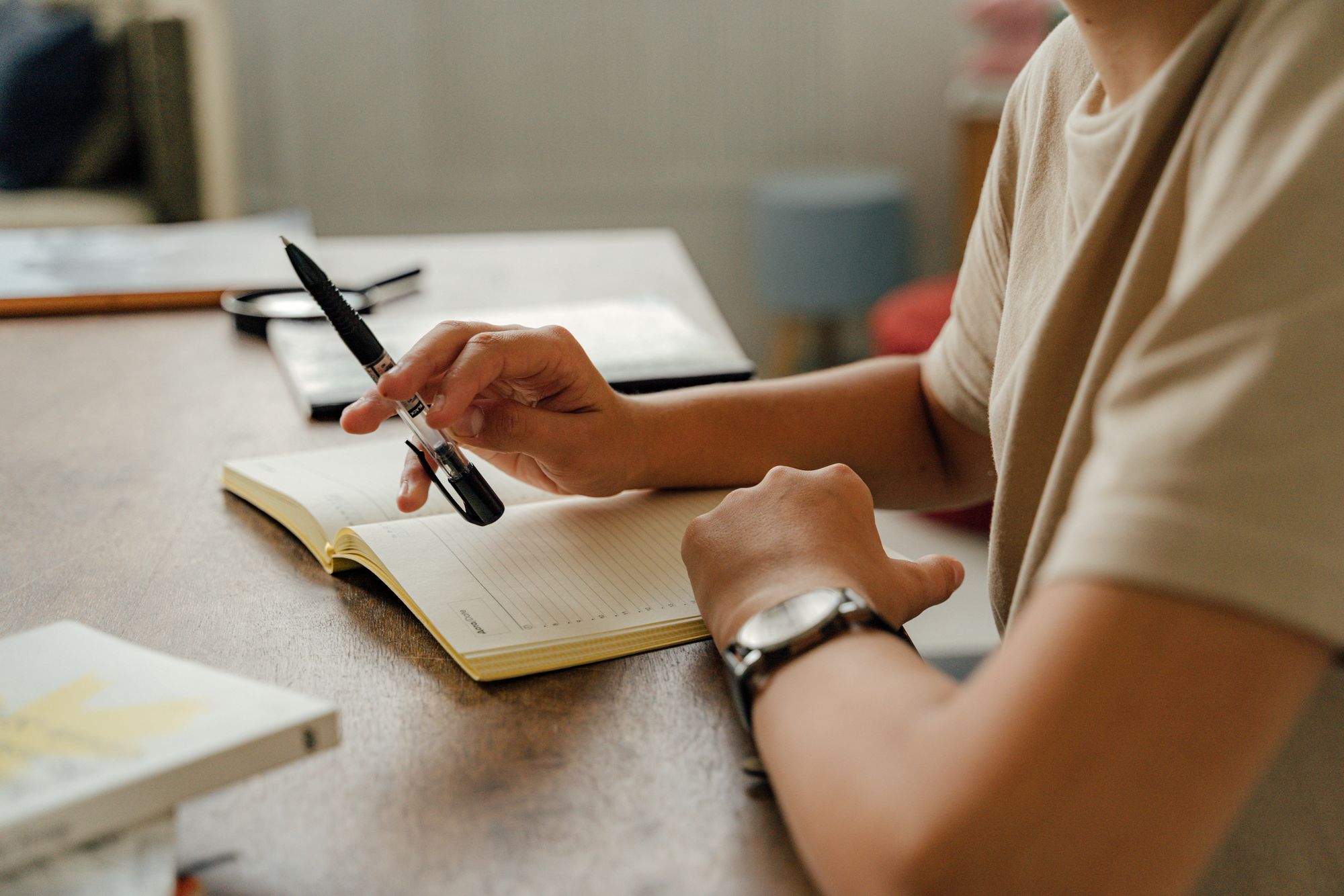 Close-up of a person writing in a notebook by lamplight in the evening