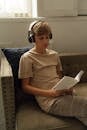 A Boy Reading a Book while Listening to Music