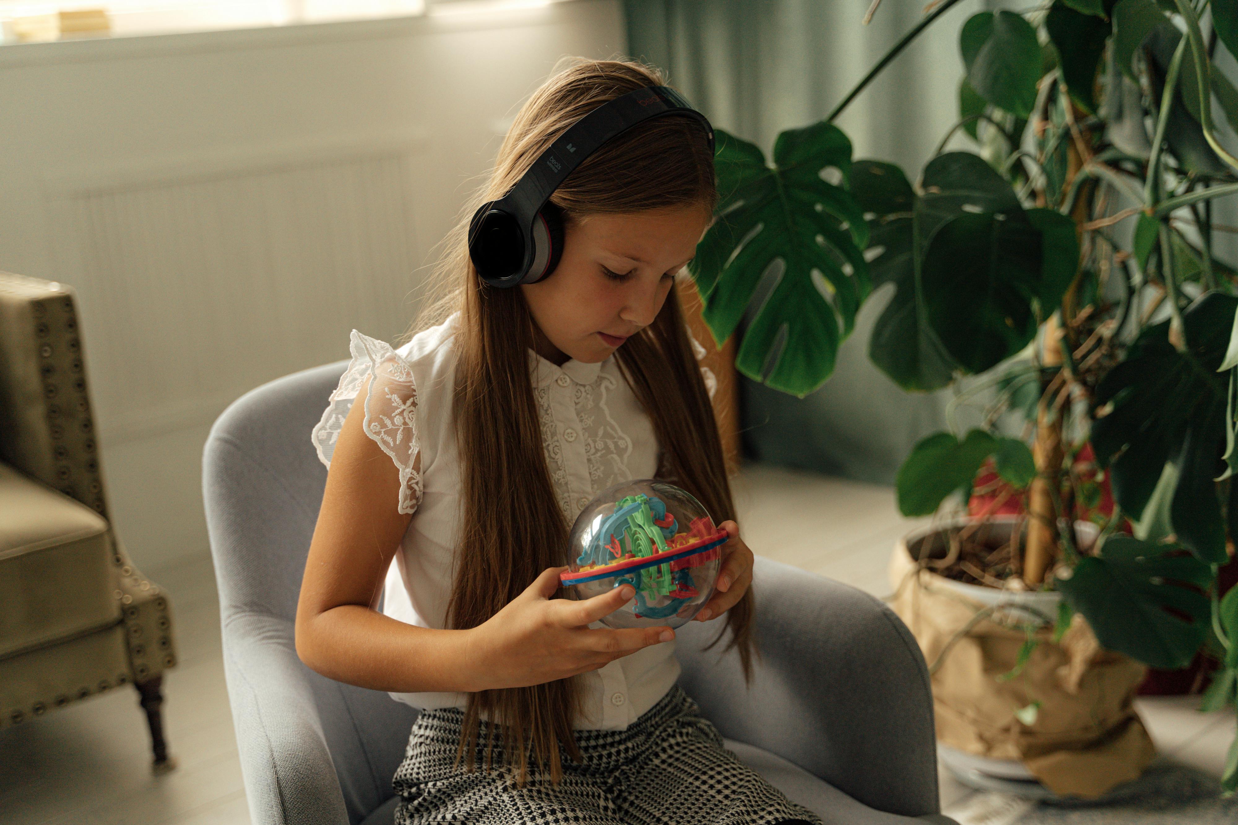 young girl wearing headphones holding a toy