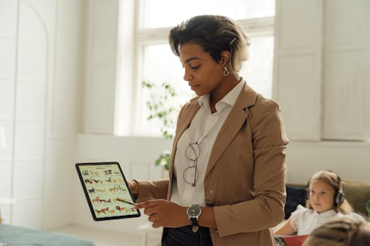 A teacher using a tablet in a bright classroom to explain a lesson to a student.