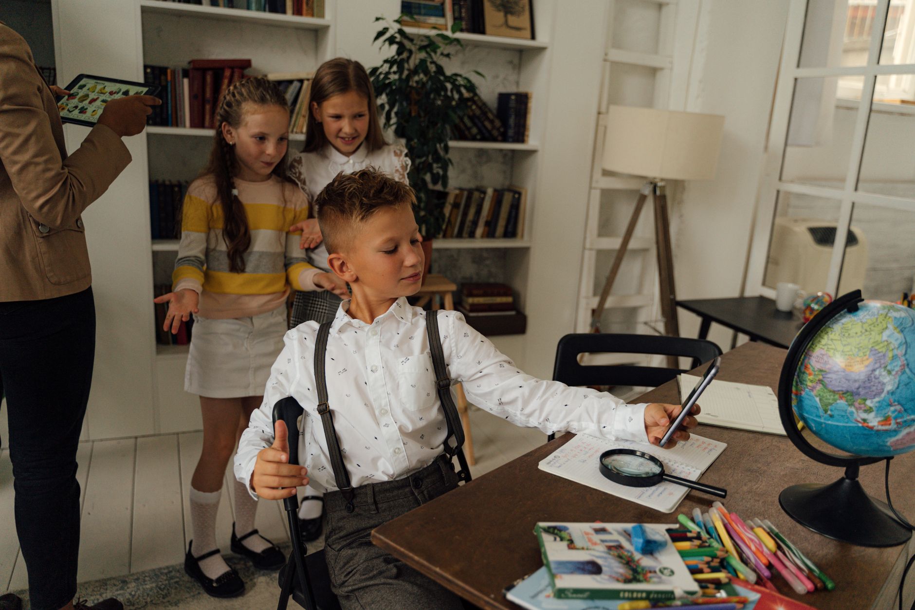 Group of children learning with school materials and technology in a classroom setting.