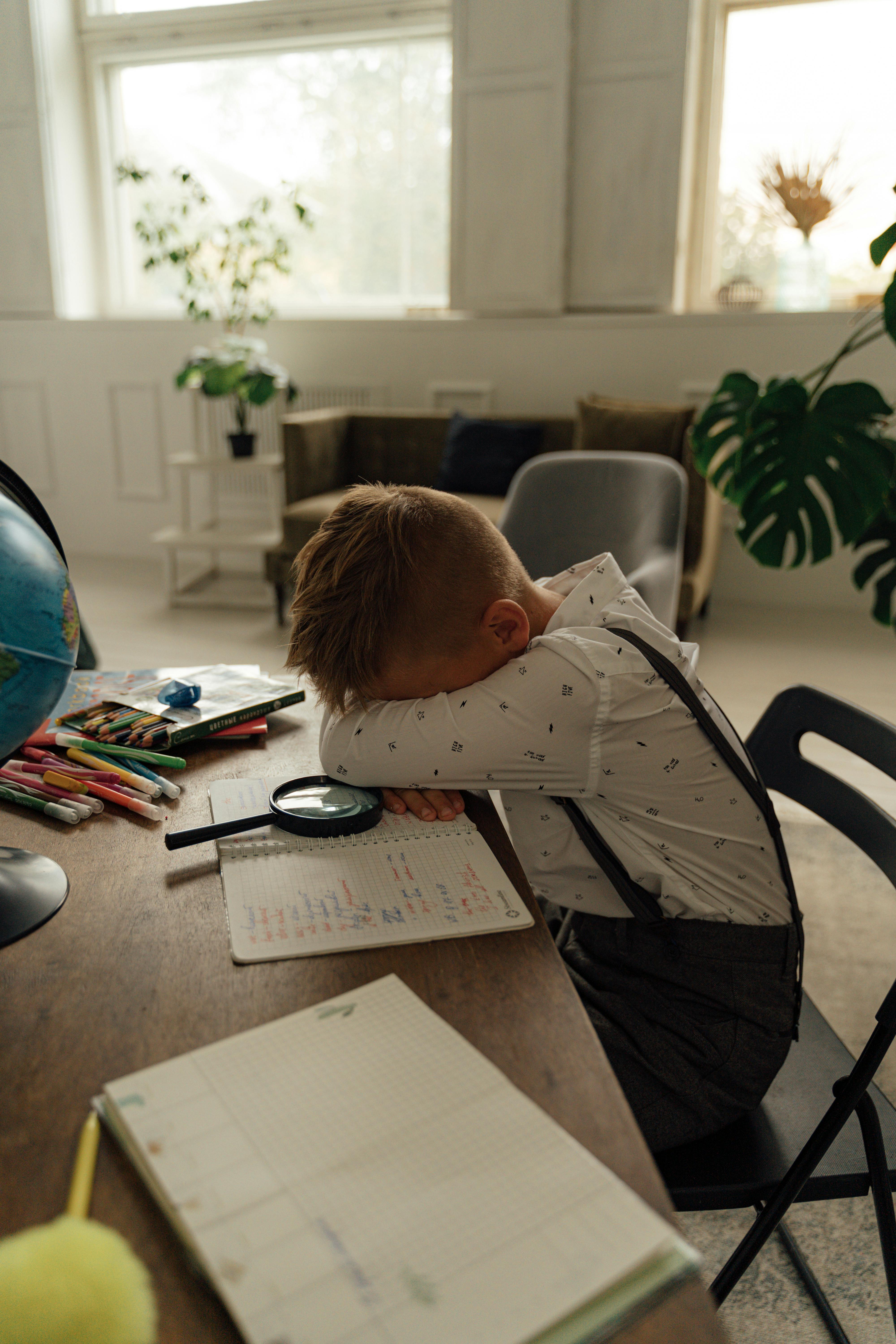 a boy leaning his head on the table