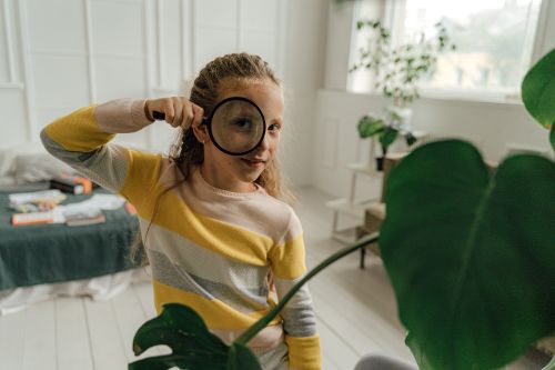 Free Curious child in a bright room examining the world with a magnifying glass. Stock Photo