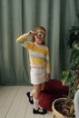 Woman in Yellow and White Striped Long Sleeve Shirt Sitting on Red Sofa