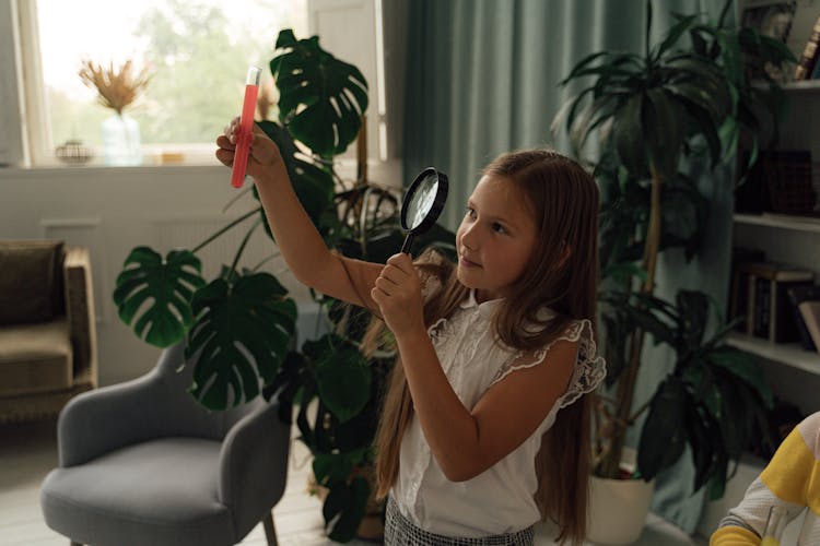 A Girl In White Blouse Observing The Chemical On The Test Tube Using A  Magnifying Glass