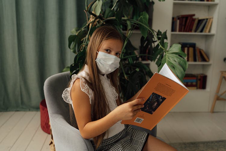 Girl Wearing Facemask Holding A Book 