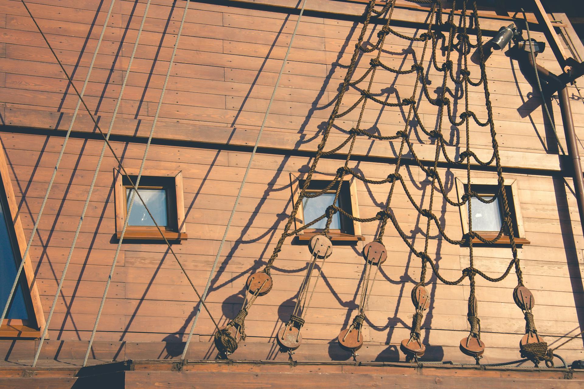 Detailed view of rope rigging and wooden ship exterior with shadows.