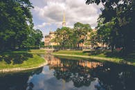 米哈伊洛夫斯基城堡的倒影映在圣彼得堡一条宁静的运河上，周围环绕着郁郁葱葱的绿色植物