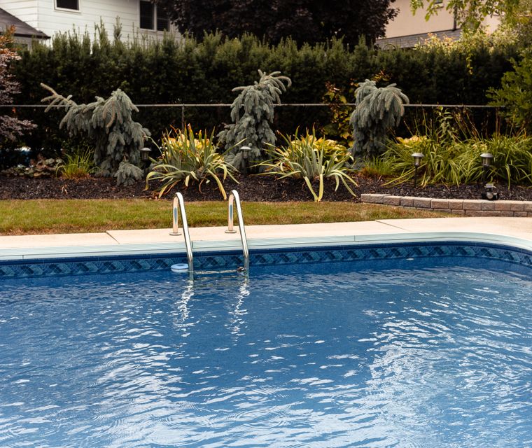 Backyard swimming pool beside a house