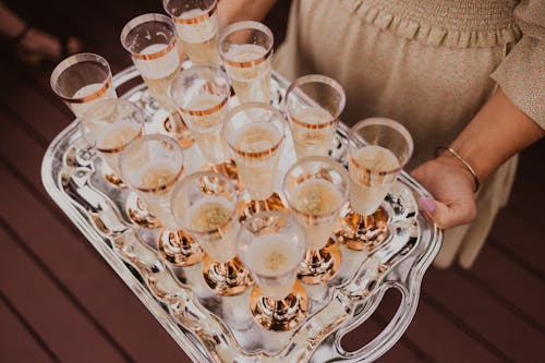 Free From above of crop female holding tray with glasses of champagne in daylight Stock Photo
