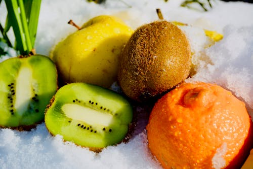 Sliced Kiwi Fruit Beside Orange in Snow