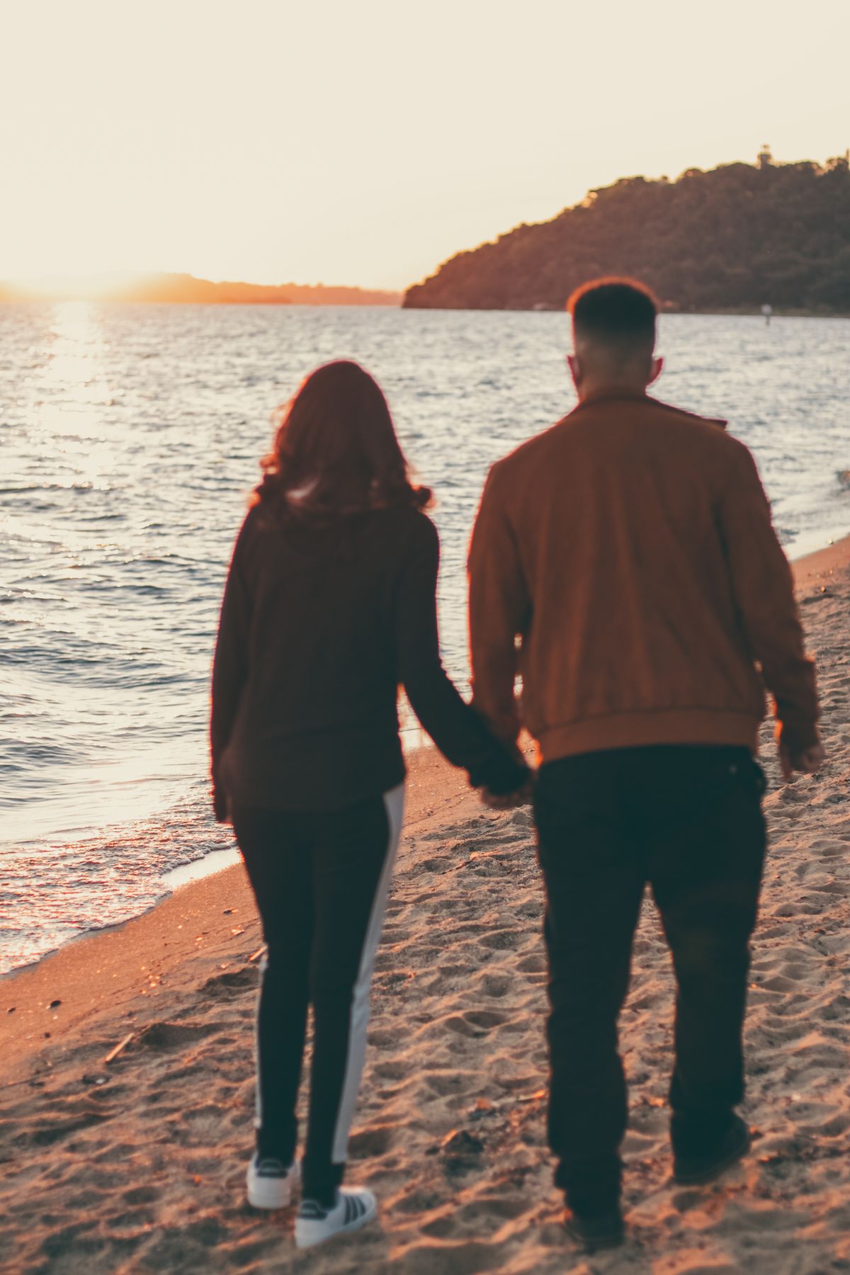 Cuplu plimbându-se pe plajă la apus, vacanță romantică