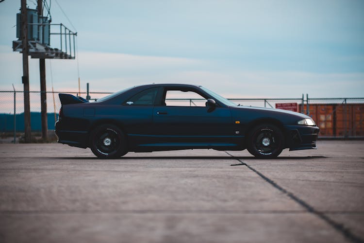 Old Sports Car On Road Under Cloudy Sky