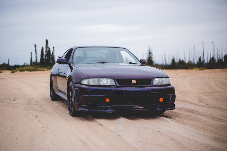 Sports Car On Sandy Terrain Under Cloudy Sky