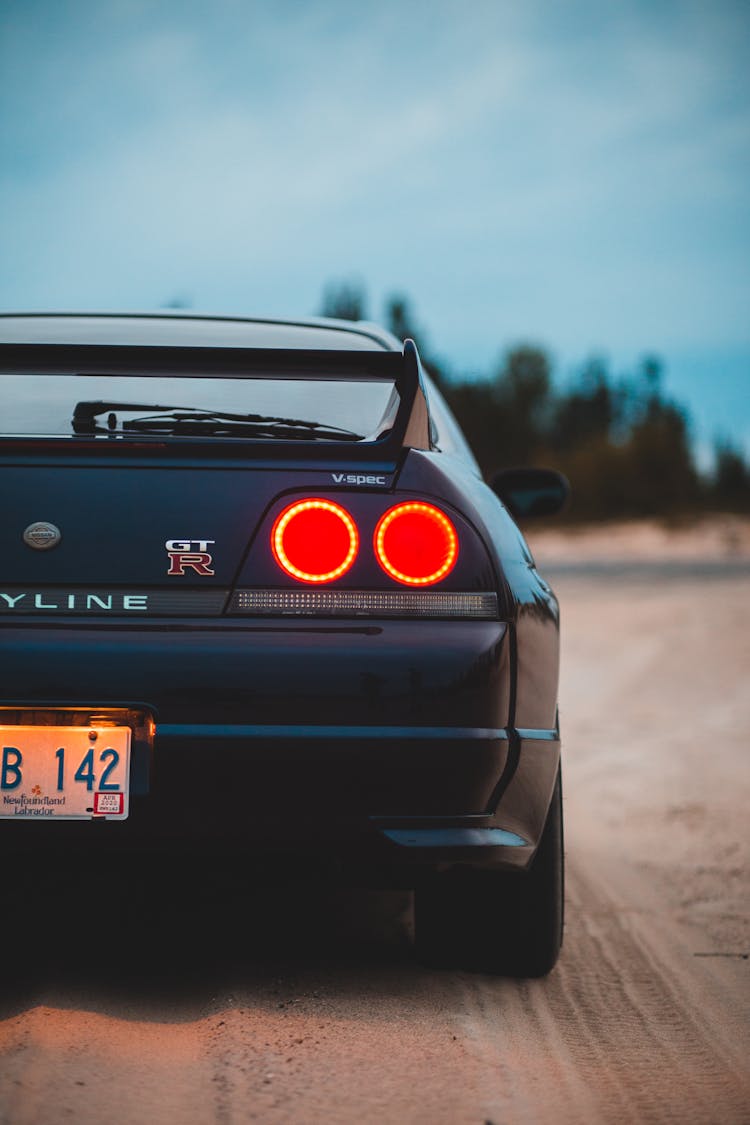 Taillights Of Sports Car On Sandy Land In Evening