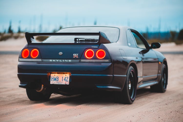 Sports Car On Sandy Terrain Under Blue Cloudy Sky