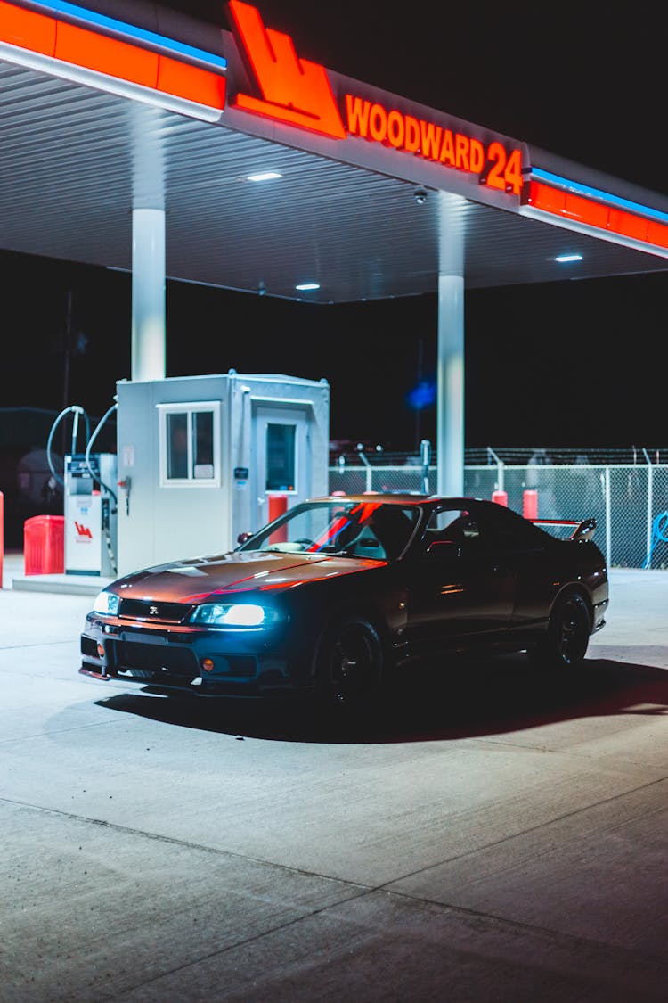 Shiny Sports Car In Bright Gas Station At Night