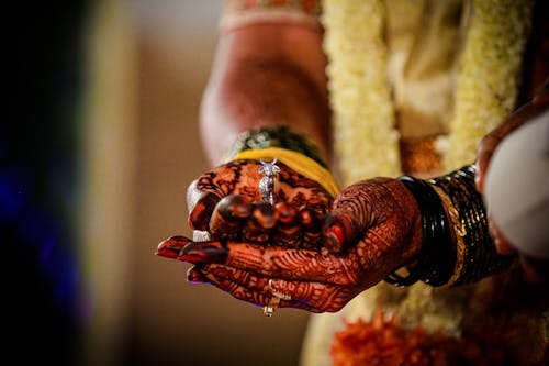 Tattooed Hands Holding a Small Silver Figurine