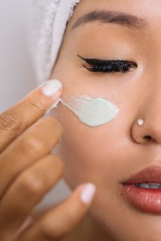 Close-up of a woman applying facial cream for skincare treatment.