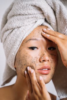 Close-up of an Asian woman applying a facial scrub, focusing on skin care and pampering.