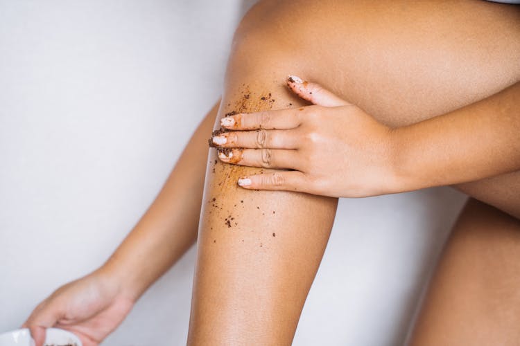 A Hand Applying Scrub On Her Leg