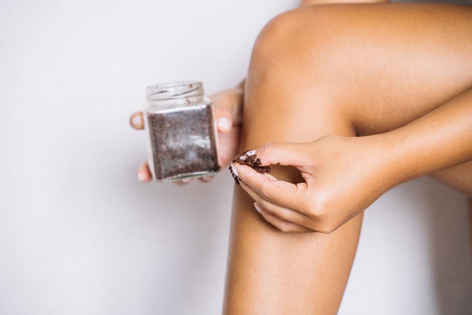 Close-up of a person's leg applying coffee scrub for skin exfoliation and body care.