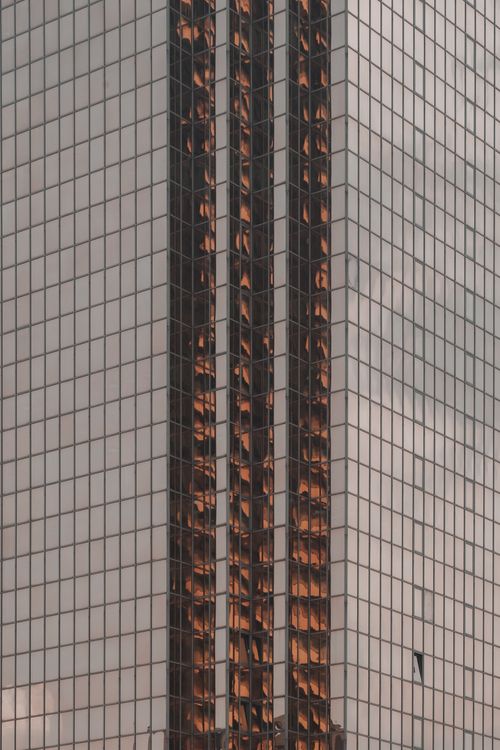 Free Close-up view of a skyscraper's reflective glass facade capturing warm sunlight reflections. Stock Photo