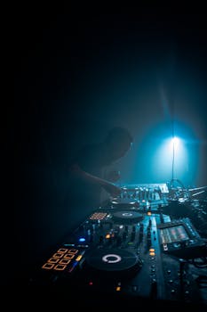 DJ mixing music on a sophisticated audio mixer in a dimly lit room.