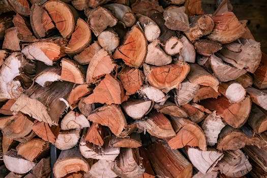 Close-up of a stacked pile of chopped firewood ready for use, showcasing natural textures and warm tones.