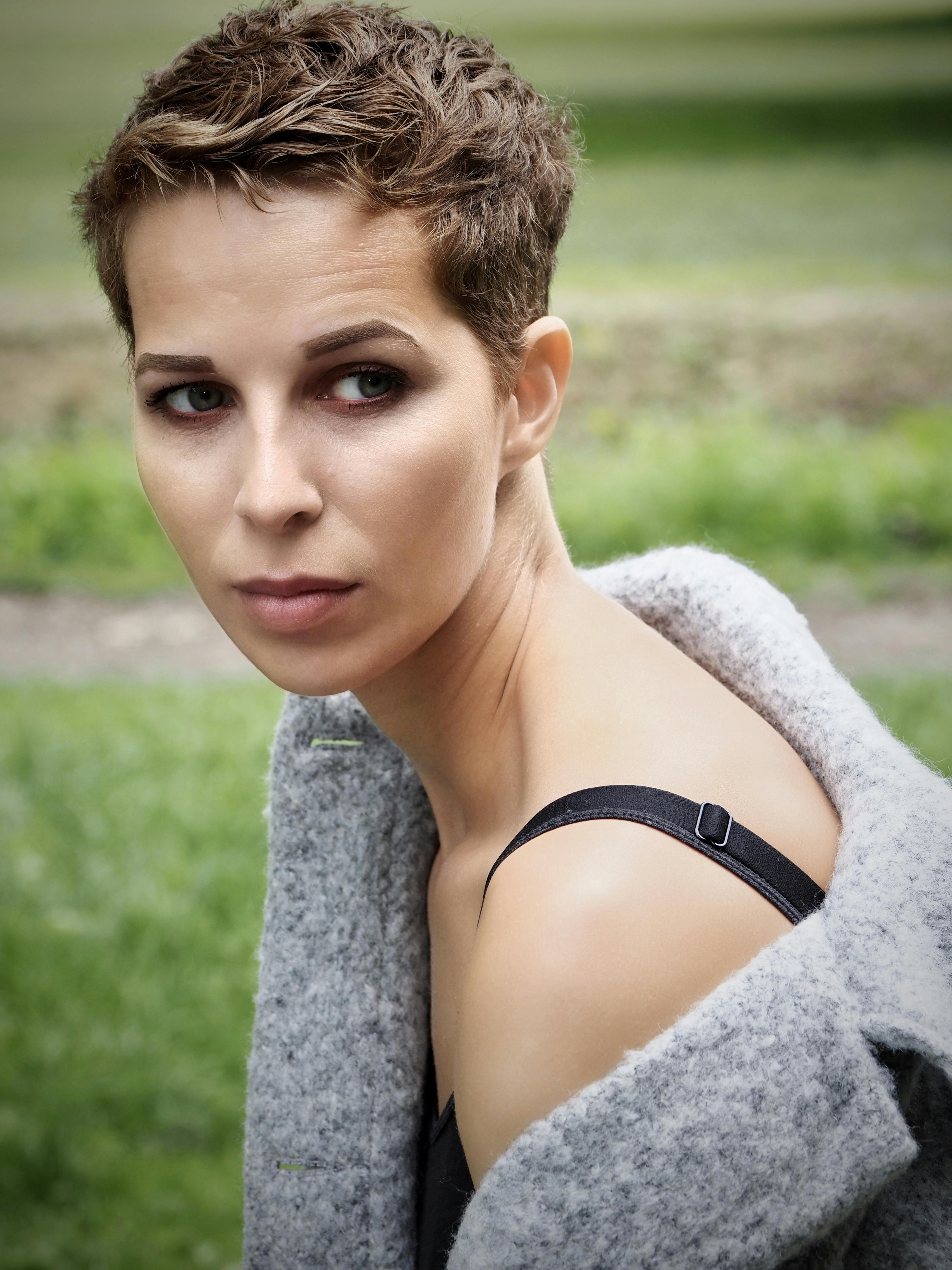 Portrait of a woman with short hair in a grey coat, set against a green park in Leeds, England.