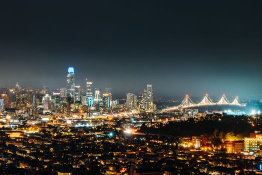 Aerial view of megapolis with residential district located near modern skyscrapers and suspension bridge at night