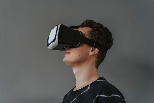 A close-up image of a man wearing a black VR headset against a gray background.