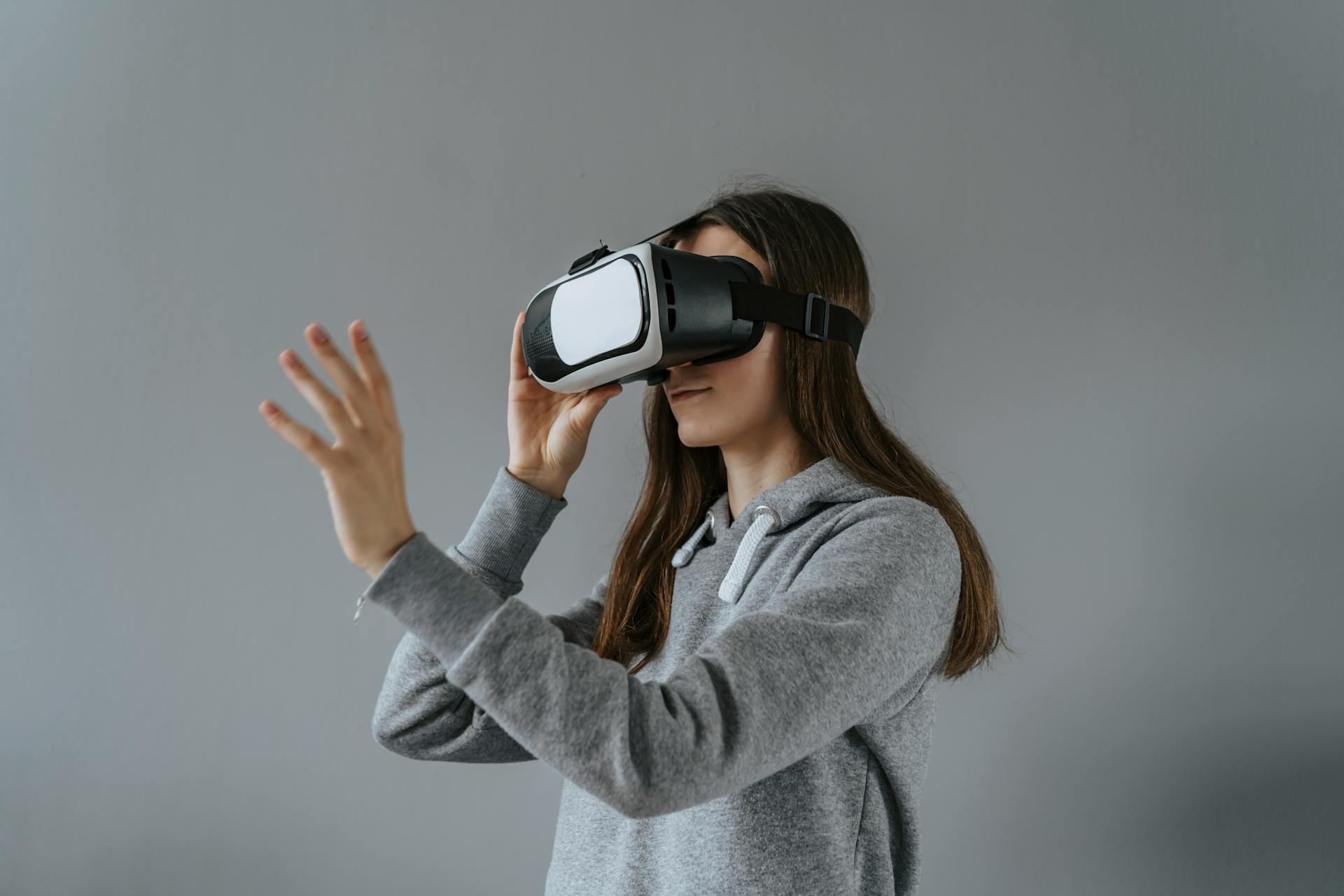 Young woman engaged in virtual reality using a VR headset indoors.