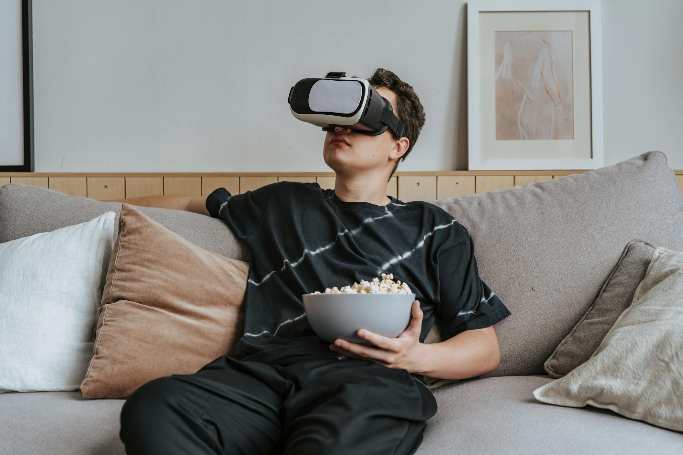 man sitting on couch playing VR game holding popcorn