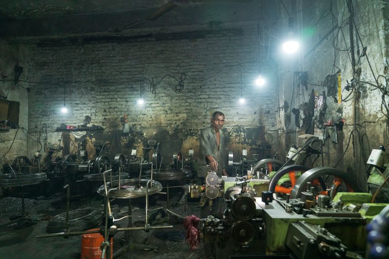 Elderly man operating machinery in a dimly lit industrial factory