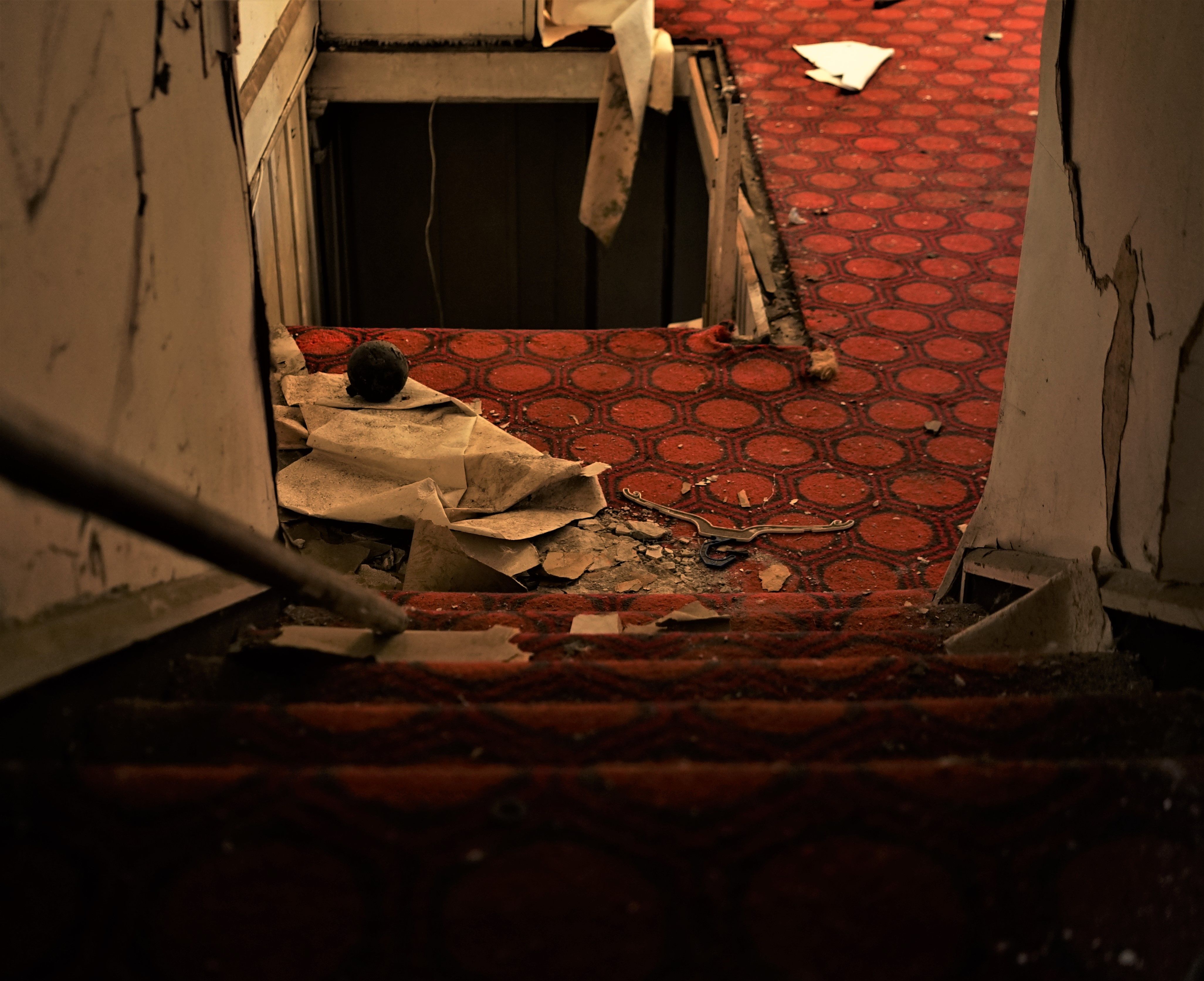 Explore the haunting atmosphere of a neglected, carpeted staircase leading into darkness inside an abandoned building.