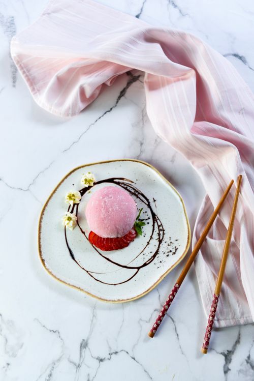 Free Elegant presentation of pink mochi on marble with chopsticks, perfect for Asian cuisine themes. Stock Photo