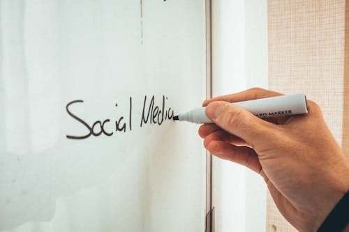 Crop anonymous male teacher writing on whiteboard with marker during social media training courses