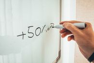 在白板上手写“+ 50%”的特写镜头，用以传达教育或商业概念