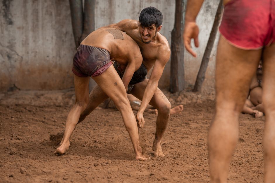 Two men engage in traditional mud wrestling, showcasing strength and technique.