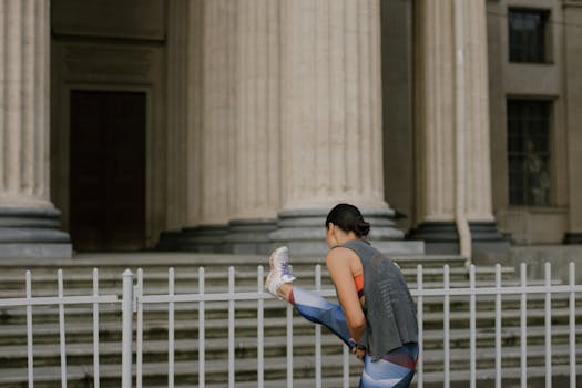 A woman stretching by a metal fence in front of historic columns, demonstrating fitness and wellness.