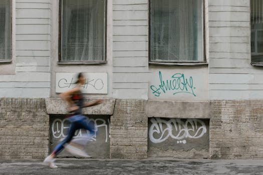 Blurred motion of a woman running past a graffiti-covered urban wall. Captures dynamic energy.