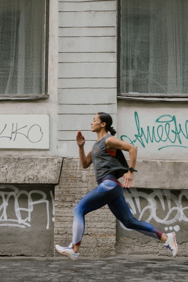 Runner striding past a painted city wall, photo by cottonbro studio on Pexels
