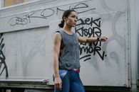 Woman in Gray Tank Top and Blue Denim Shorts Standing Near White Wall