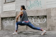 Woman in Gray Tank Top and Blue Leggings Doing Yoga