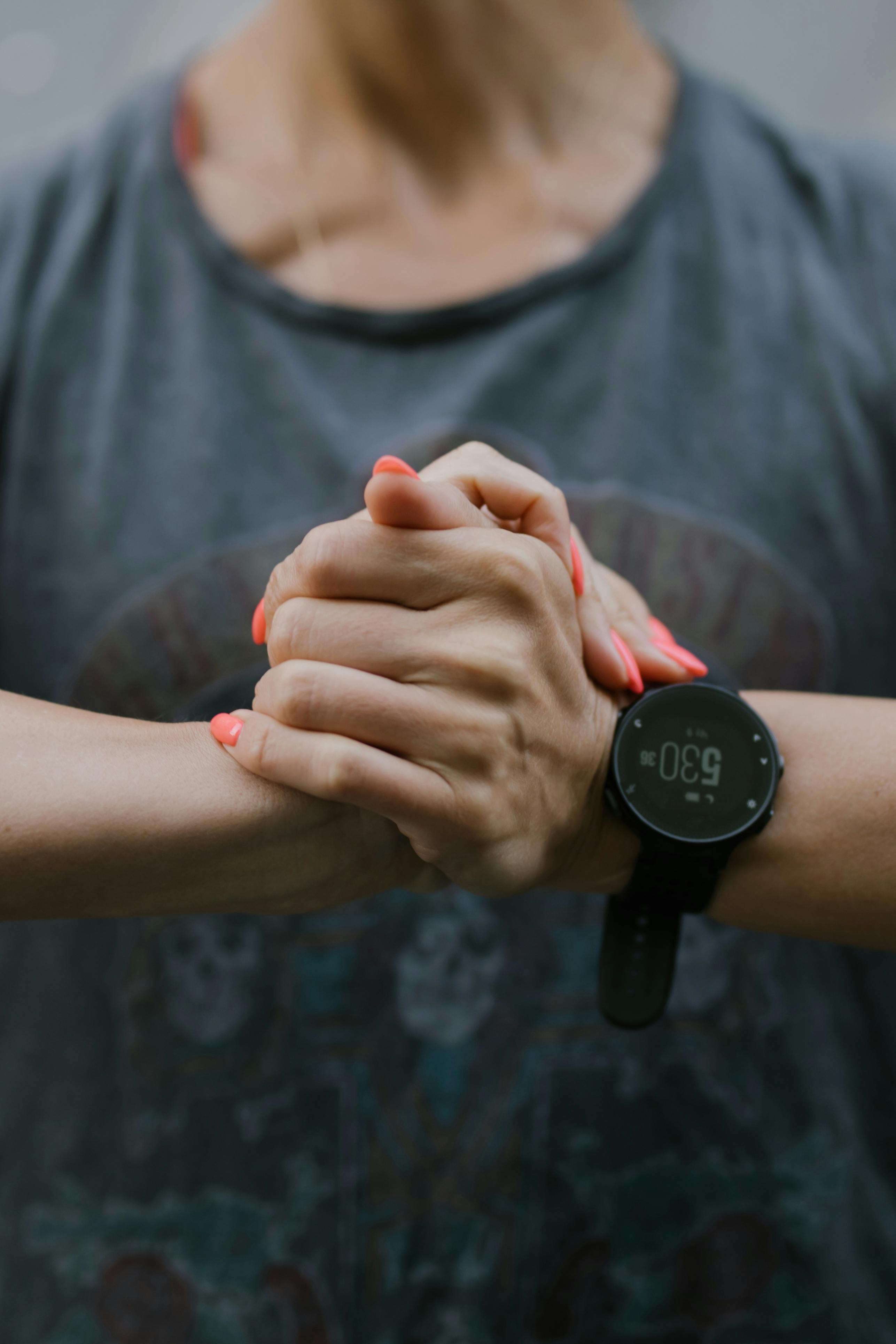 Close-up of a woman's hands with a smartwatch, showcasing casual style and modern technology.