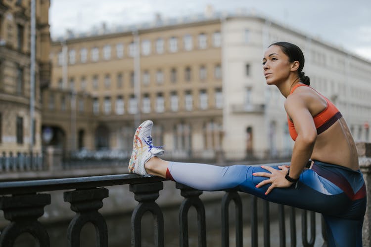 A Woman Stretching Her Legs On The Railing