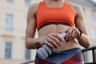Woman in Red Sports Bra and Blue Shorts Holding White and Blue Bottle