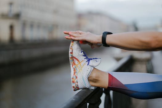A person stretching their leg with colorful shoes by a canal in an urban setting.